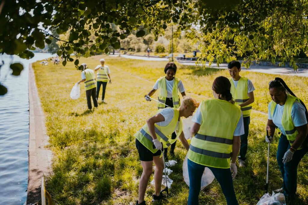 Group of volunteers in high visibility vests cleaning in a field.