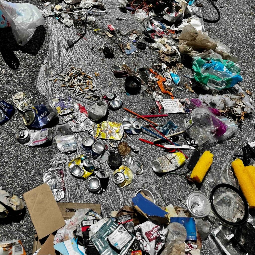 A collection of trash items, including cans, bottles, bags and cigarette butts.